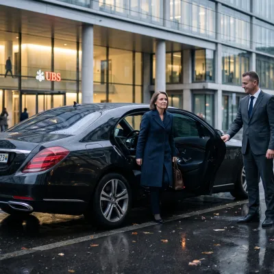 Schwarze Executive-Limousine vor einem Firmensitz in Zürich, Chauffeur öffnet die Fondtür